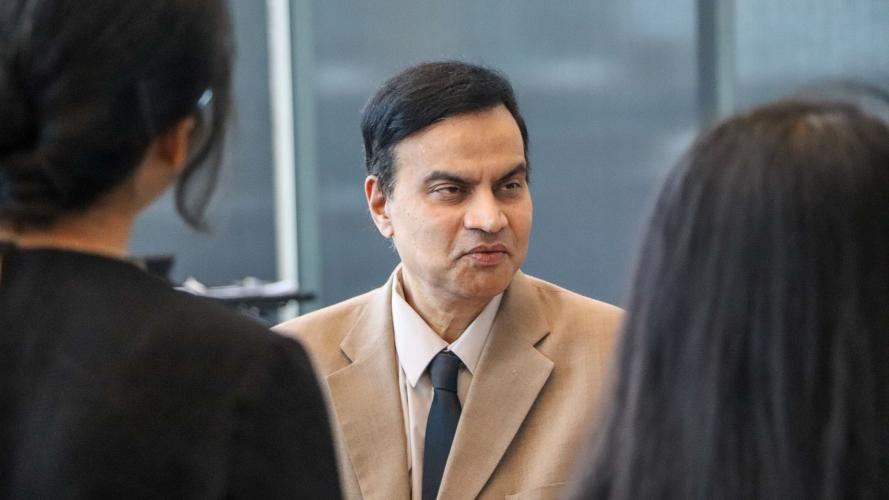 A man in a suit speaking with two students. 