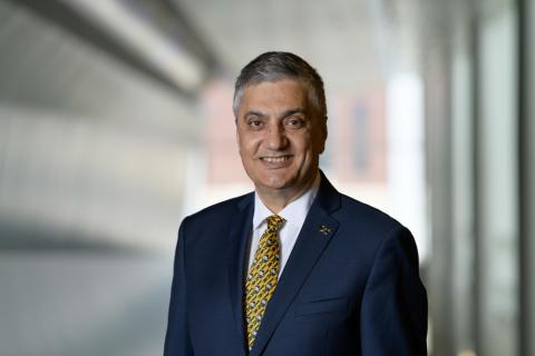 Headshot of Chaouki Abdallah wearing a navy suit jacket and gold-patterned tie with a white a shirt. Chaouki is smiling.