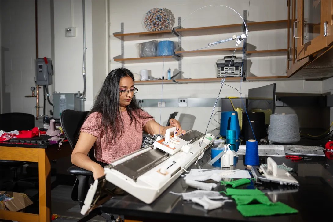 Krishma Singal sitting at a knitting machine